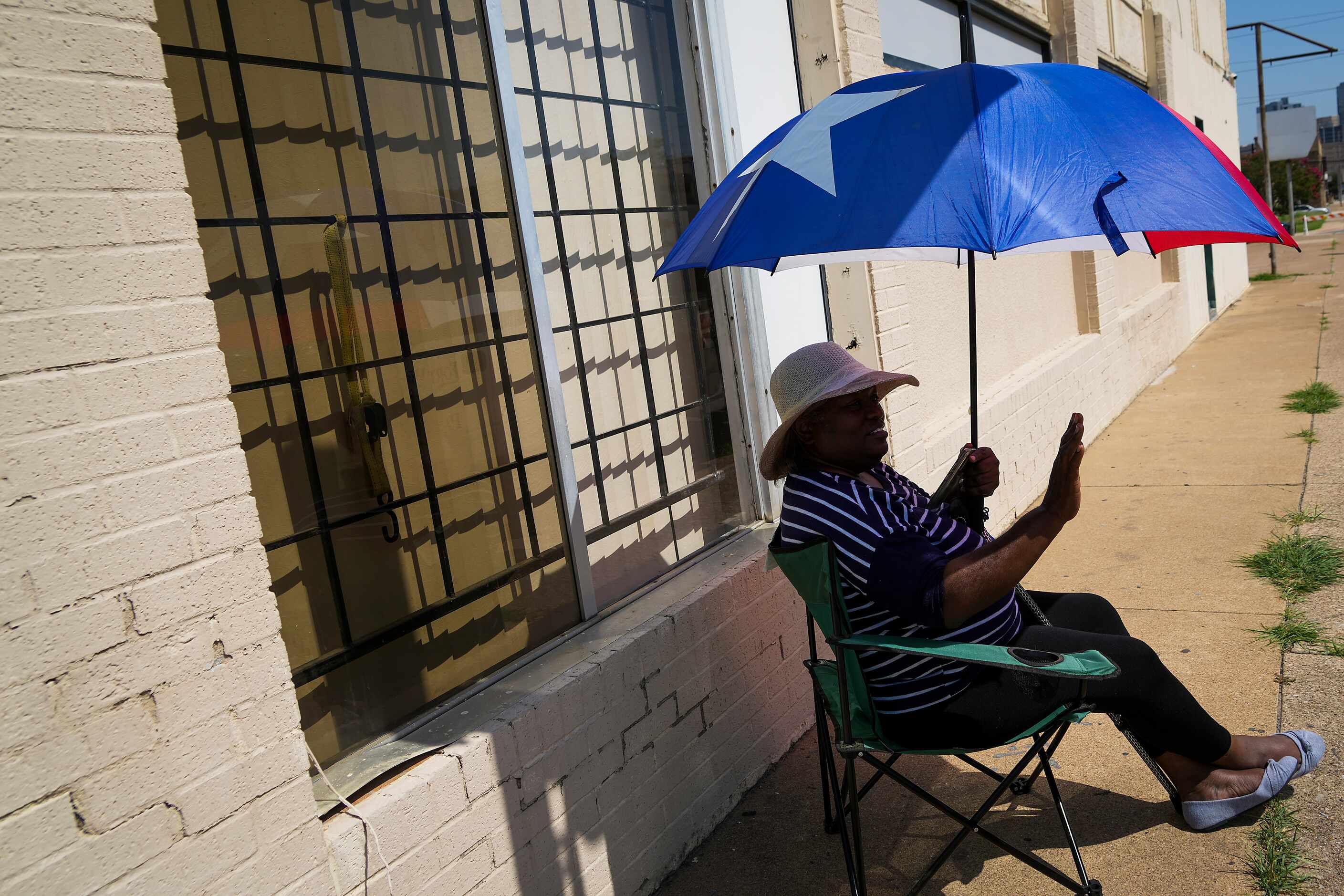 Betty Blaylock finds shade under a Texas flag themed umbrella as she cheers the 2022 Opal's...