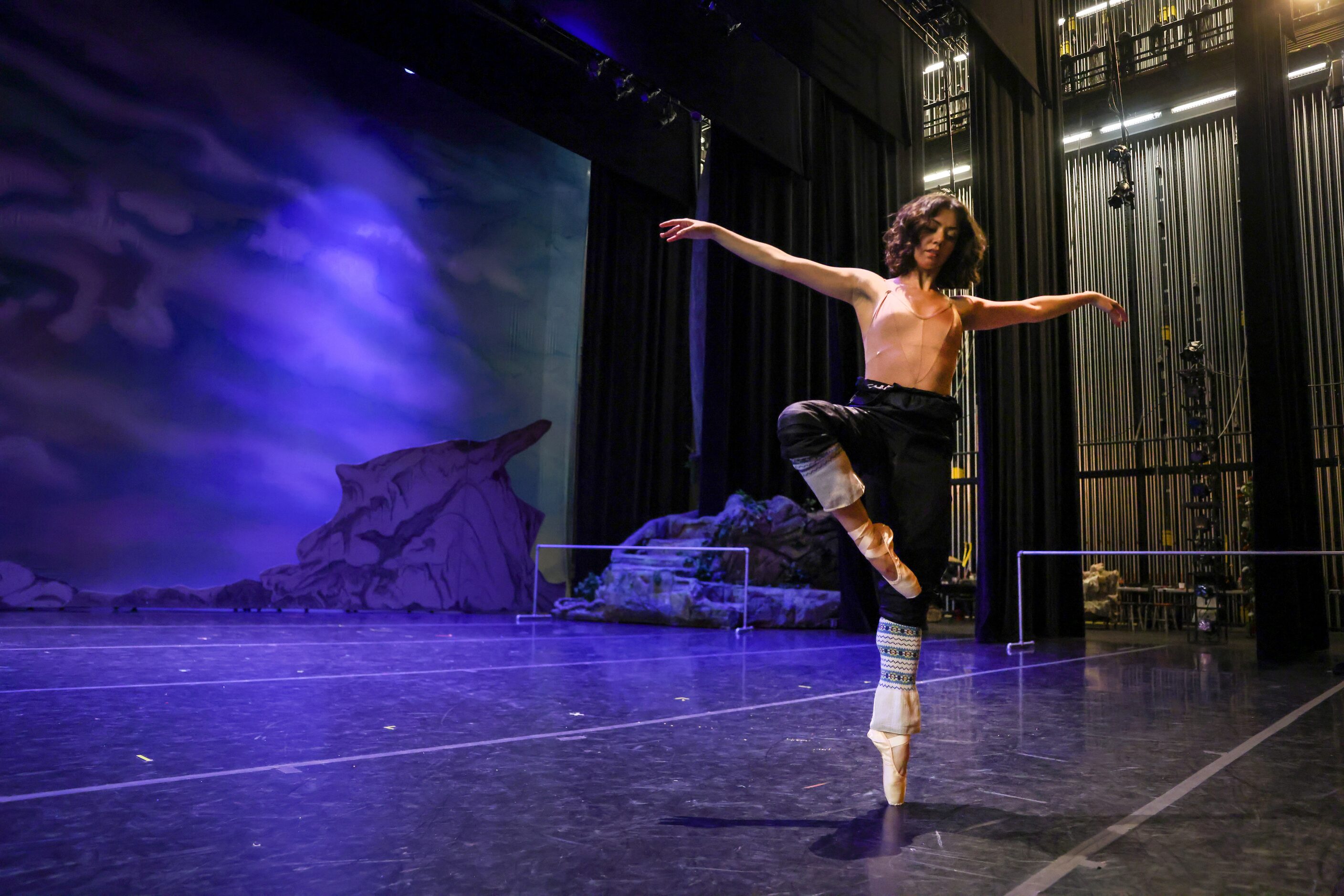 Alexandra F. Light transitions to her pointe shoes as she warms up on an empty stage for her...