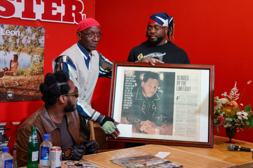 Lloyd V. Coleman shows Leon Bridges a framed copy of a Dallas Morning News article at an...