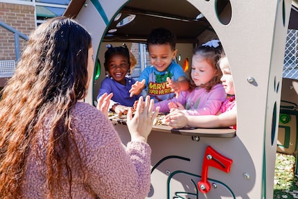 Caregiver Aline Assis plays with children outside at Little Mustangs Child Learning Academy,...