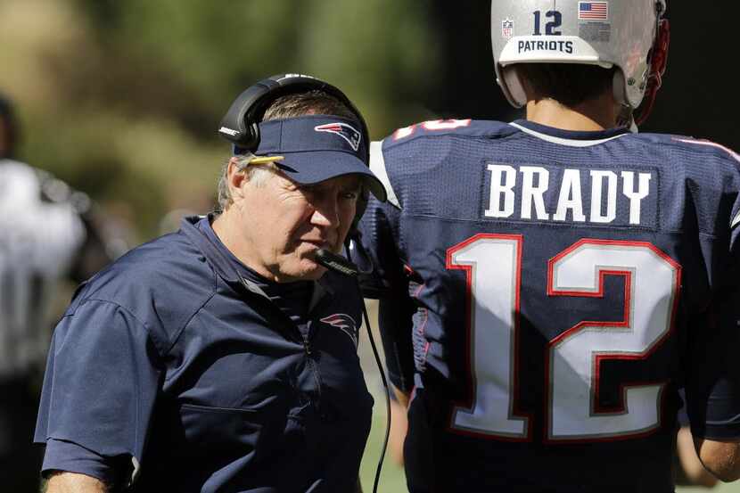 New England Patriots head coach Bill Belichick walks along the sideline beside quarterback...