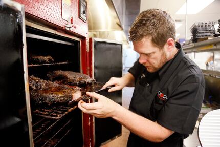 Chef Jeff Qualls checks briskets in a smoker at Hickory on June 4, 2015. The restaurant uses...
