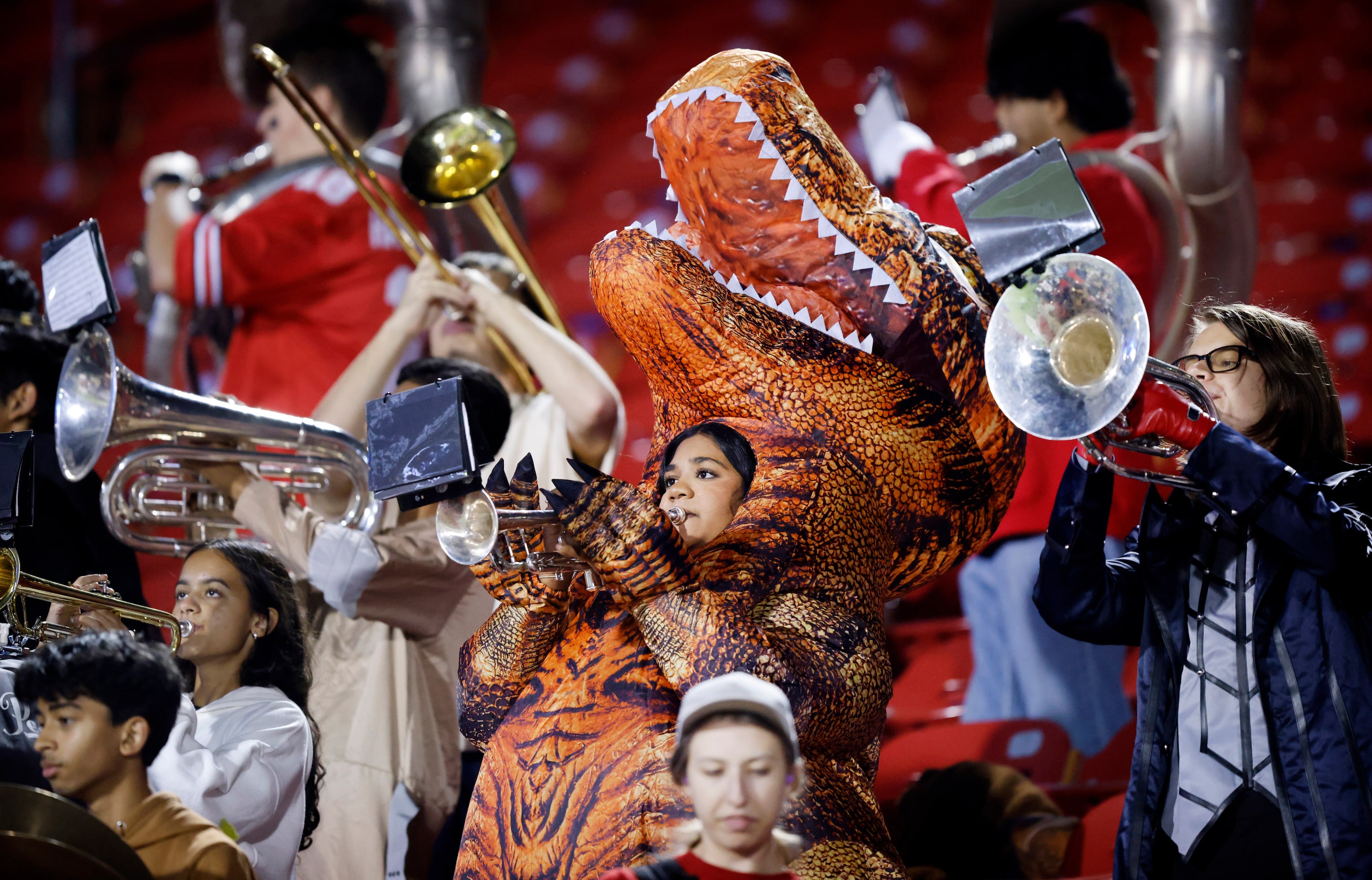 A member of the Frisco Independence marching band plays her instrument dressed as a dinosaur...