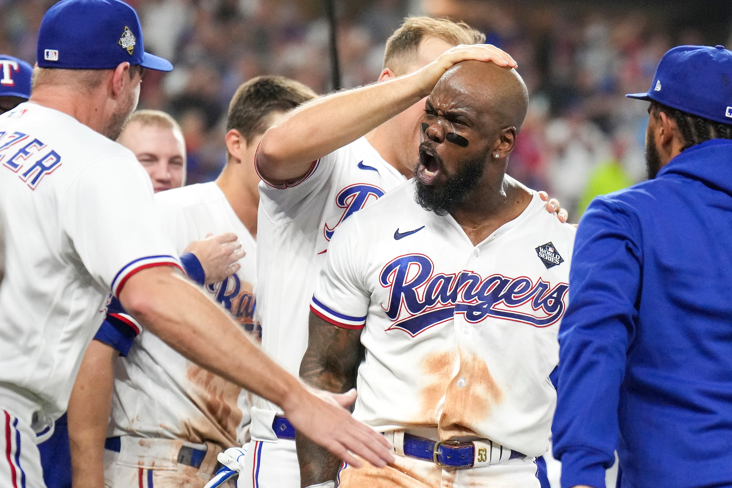 Texas Rangers' Adolis Garcia is mobbed at home plate after hitting a walk-off home run...