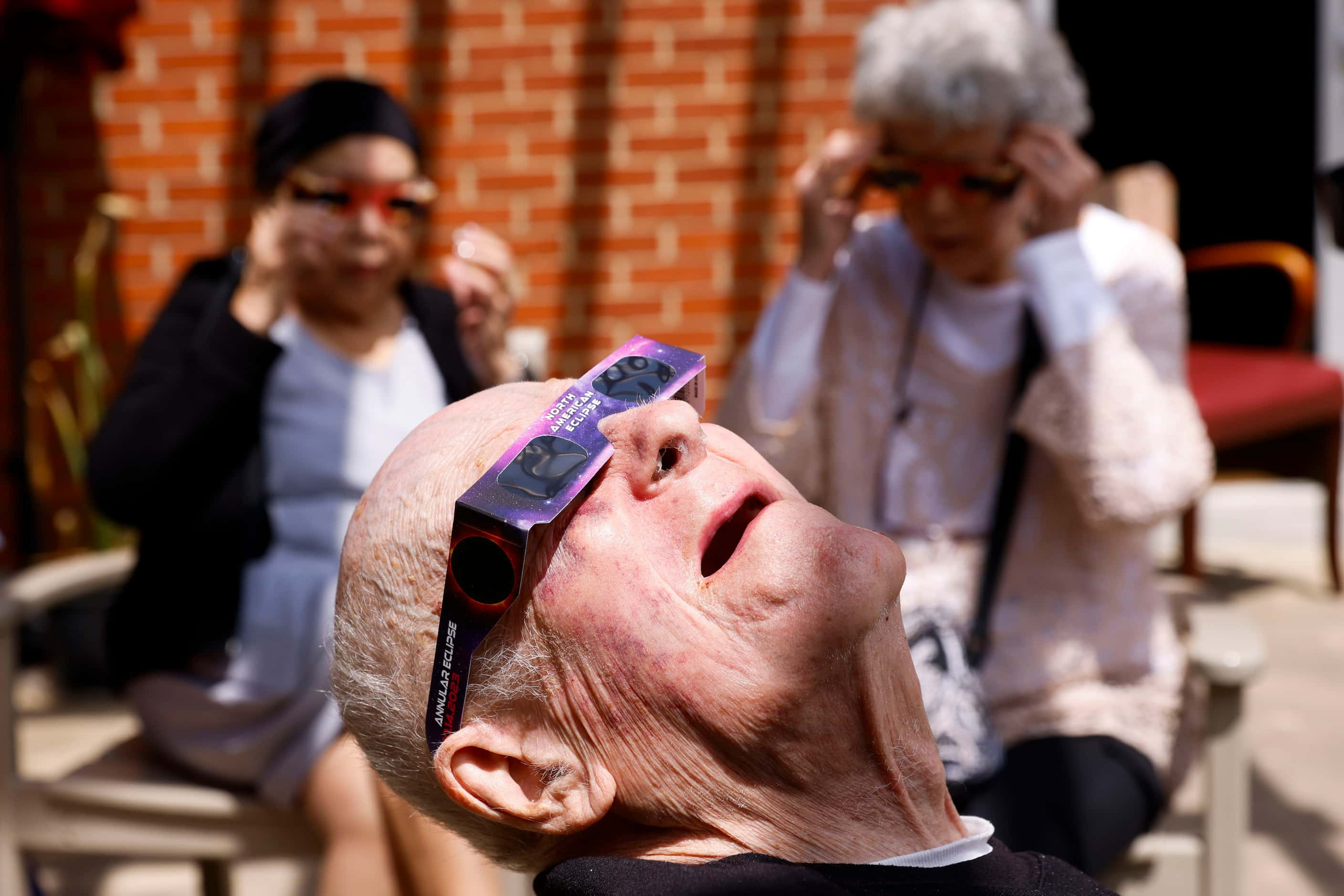 Retired Air Force personnel Glen Jaekel looks up to look at the early stage of total solar...