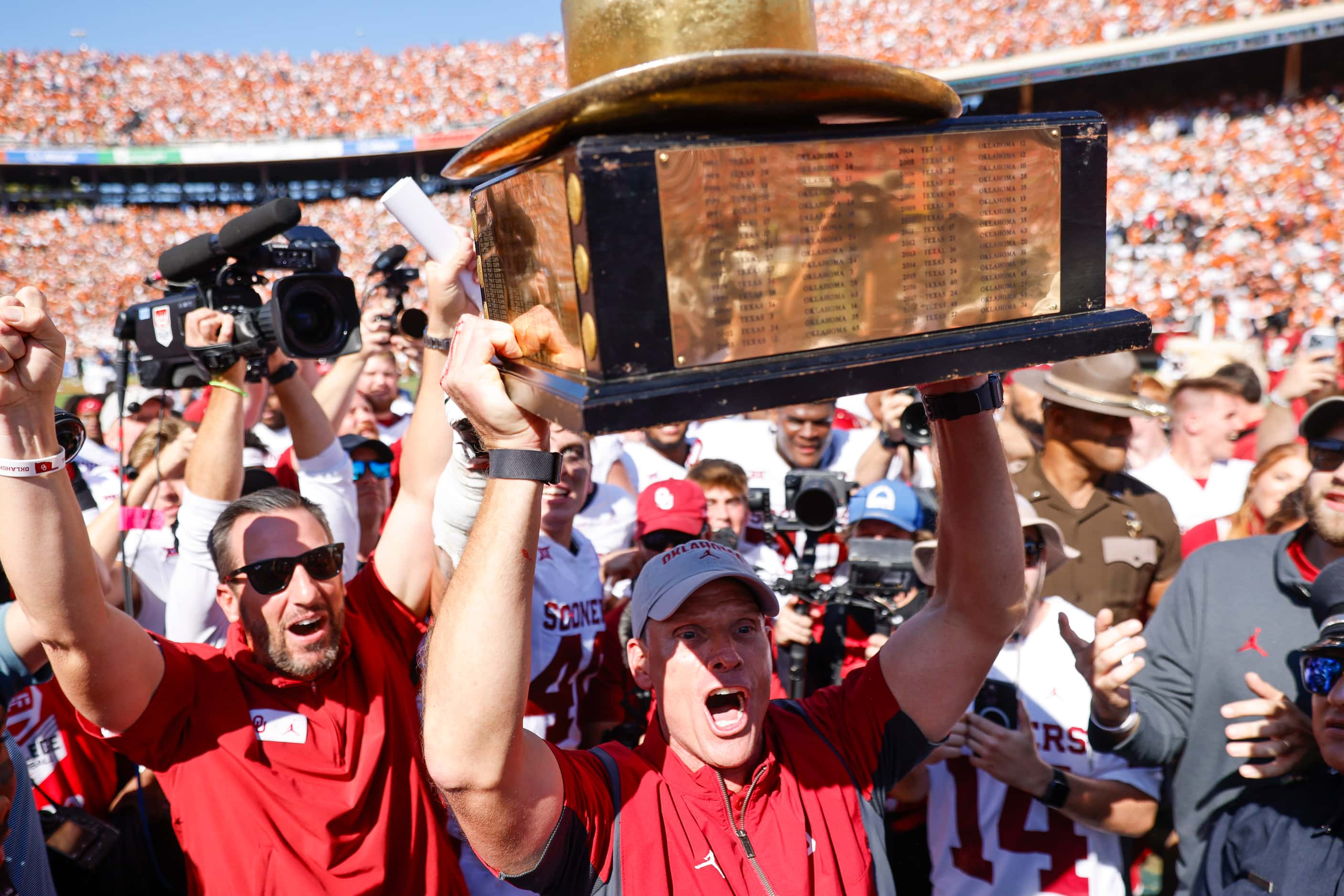 Oklahoma coach Brent Venables cheers holding the trophy after winning the Red River Rivalry...
