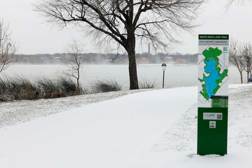 Snow covers the ground as steam rises from White Rock Lake, Monday, Jan. 15, 2024, in...