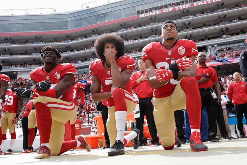 Colin Kaepernick (center) knelt during the national anthem to protest police violence...