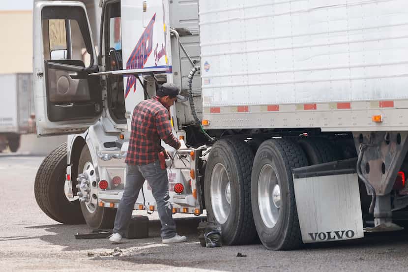 A semi-truck driver performs required repairs after being inspected by Texas state troopers...