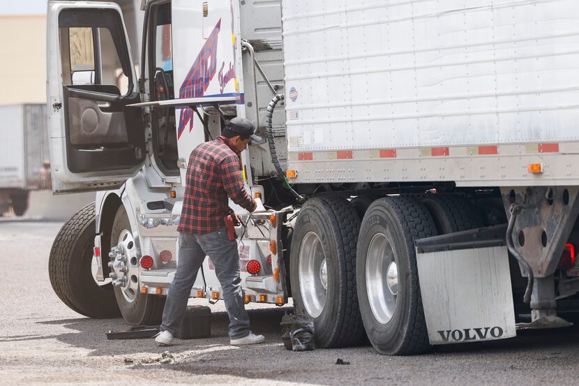 A semi-truck driver performs required repairs after being inspected by Texas state troopers...