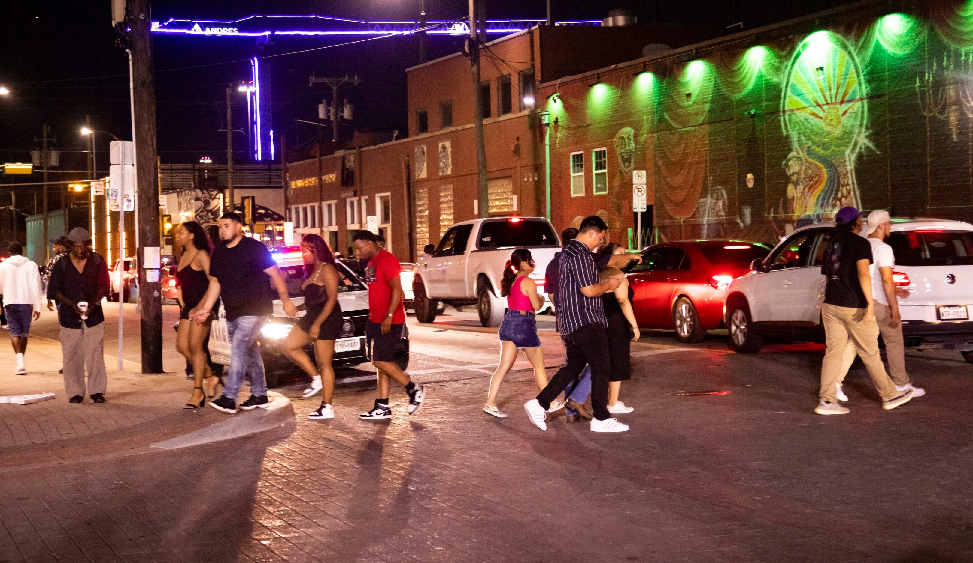 People walk in the streets as bars begin to close in the Deep Ellum district of Dallas on...