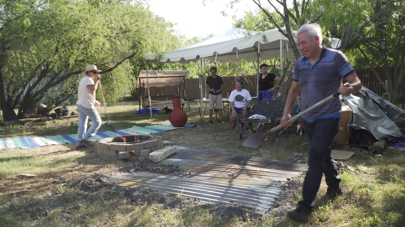 Using a centuries-old earth-oven technique, Adán Medrano (right) helps seal the pit after...