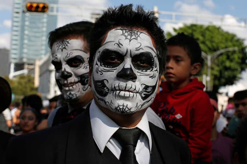Men with their faces painted as skulls took part in a Day of the Dead parade along Mexico...