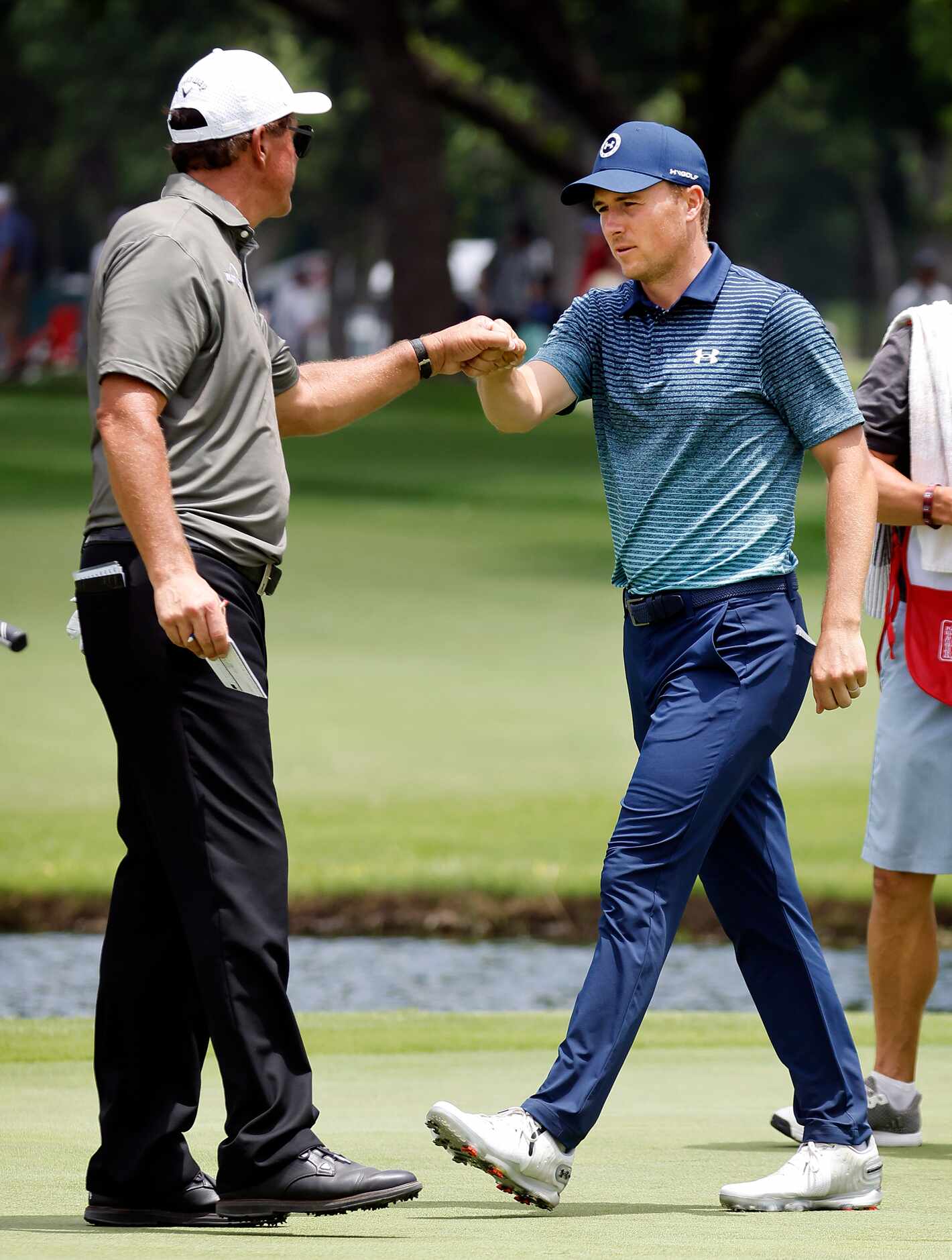 Professional golfer Jordan Spieth fist bumps Phil Mickelson on the 9th green following round...