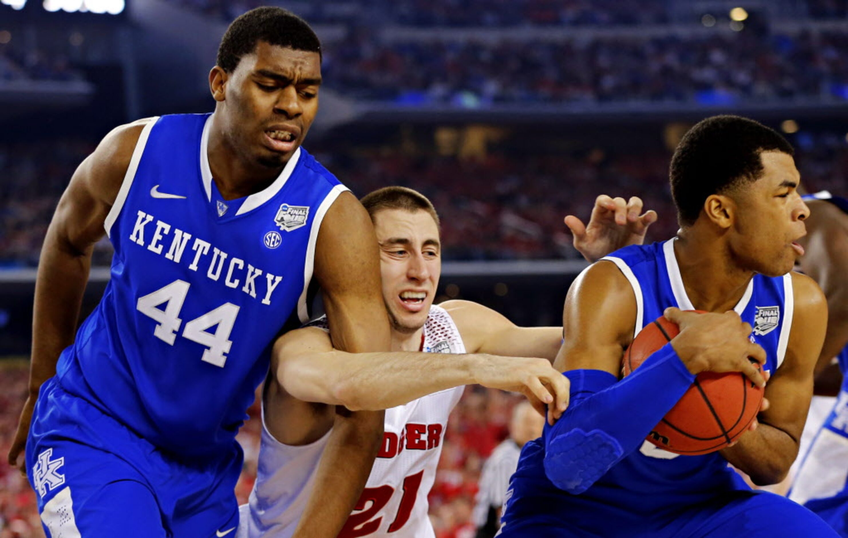 Wisconsin Badgers guard Josh Gasser (21) is wrapped up by Kentucky Wildcats center Dakari...