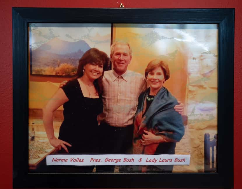 Valles poses with former President George W. Bush and Laura Bush in a photo on display in...