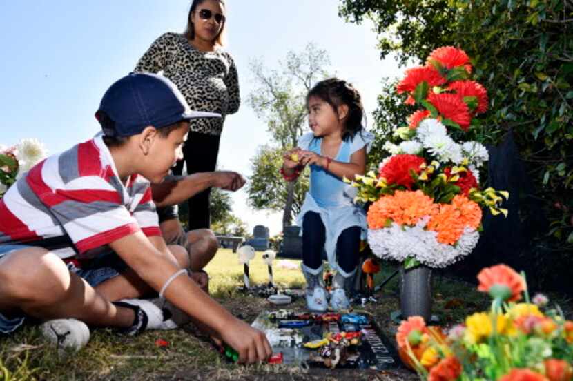 Jahir (izq.) y su hermana Gia Martínez decoran la tumba de su hermanito con juguetes durante...