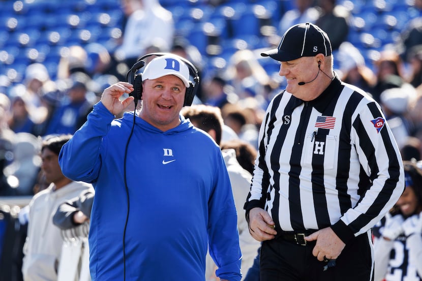 Duke head coach Mike Elko smiles with an official during the first half of an NCAA college...