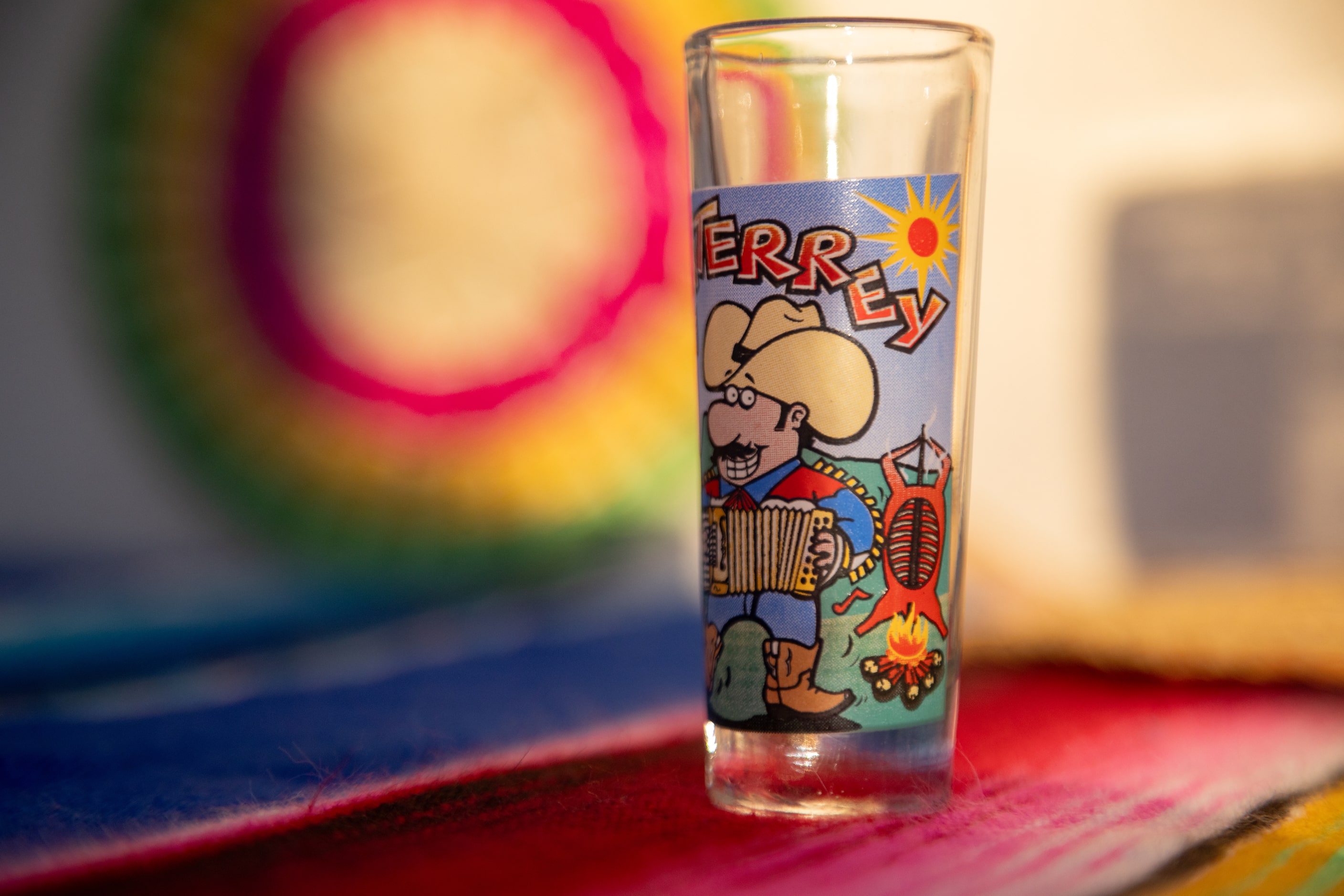 A shot glass from Monterrey features the image of a cabrito being cooked at a celebration...