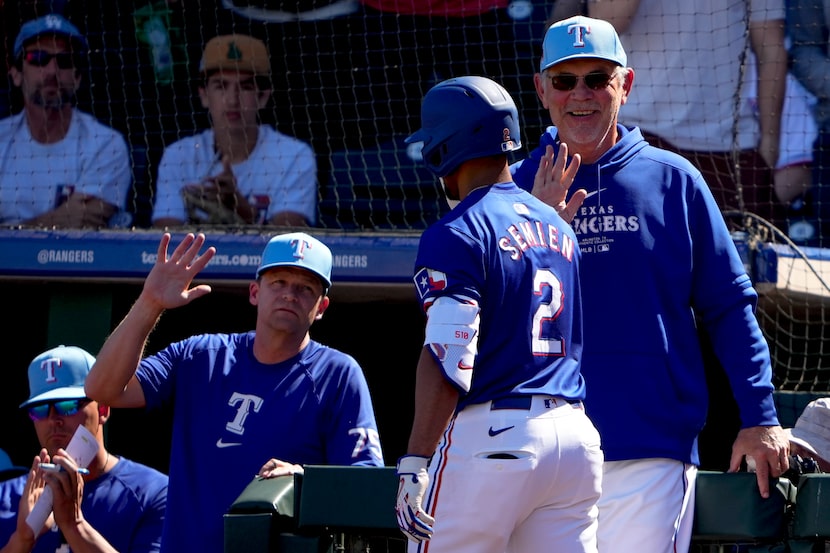 Marcus Semien (2) de los Rangers de Texas es felicitado por el mánager Bruce Bochy (derecha)...