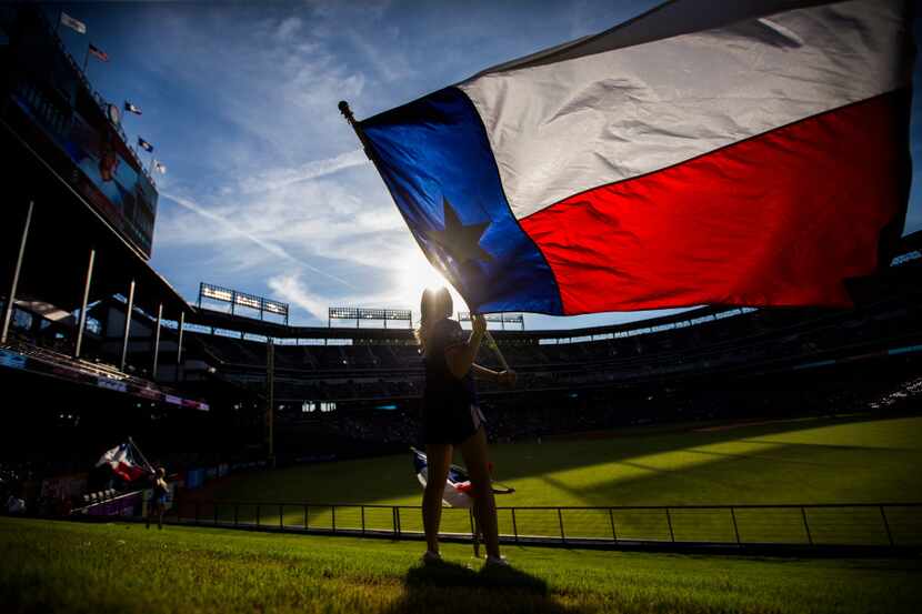 Texas Rangers Six Shooter Jaime Thatcher waves a Texas flag in the outfield before their...