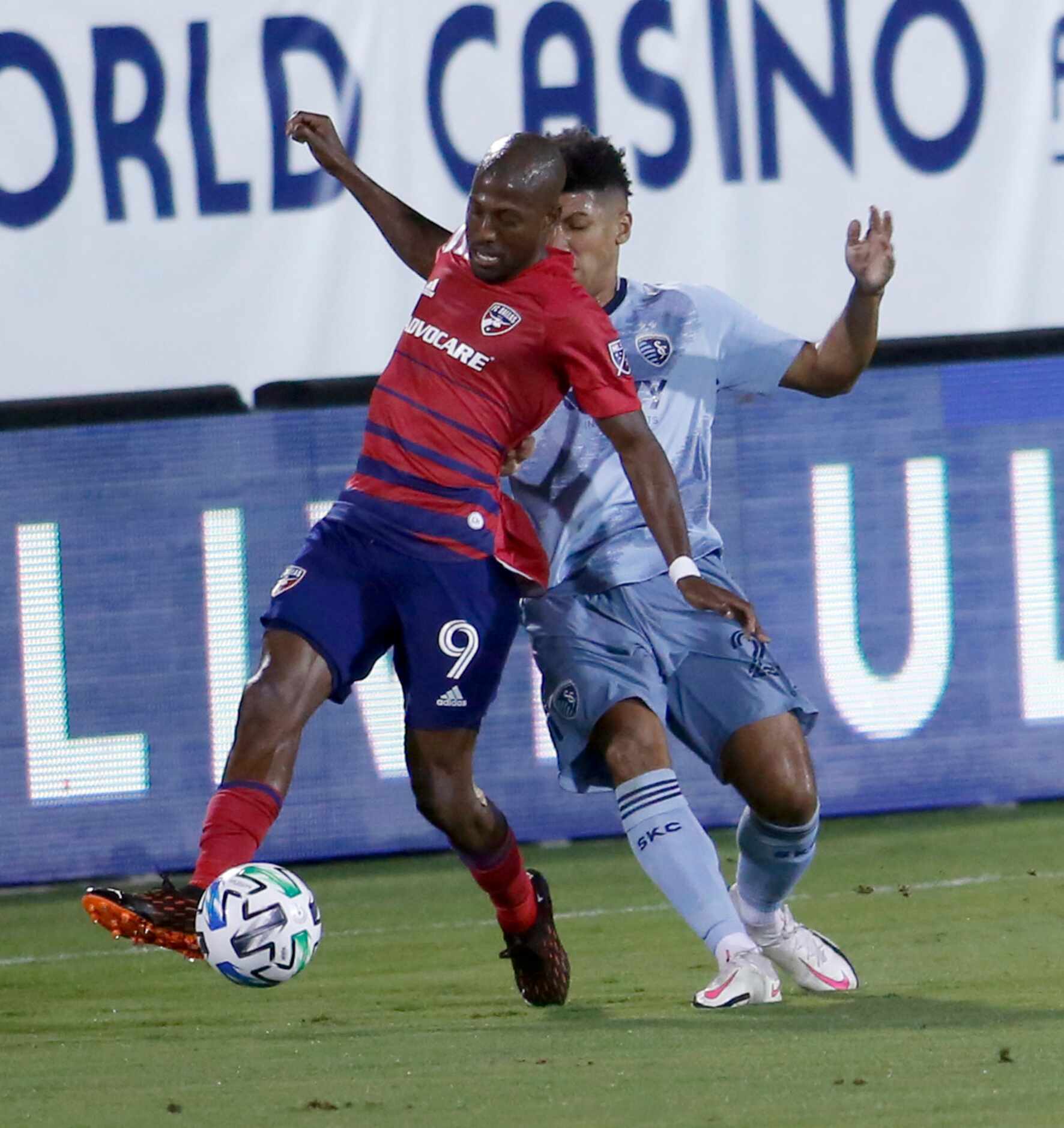 FC Dallas' Fafa Picault (9) controls the ball as he is defended by Sporting KC's Jaylin...