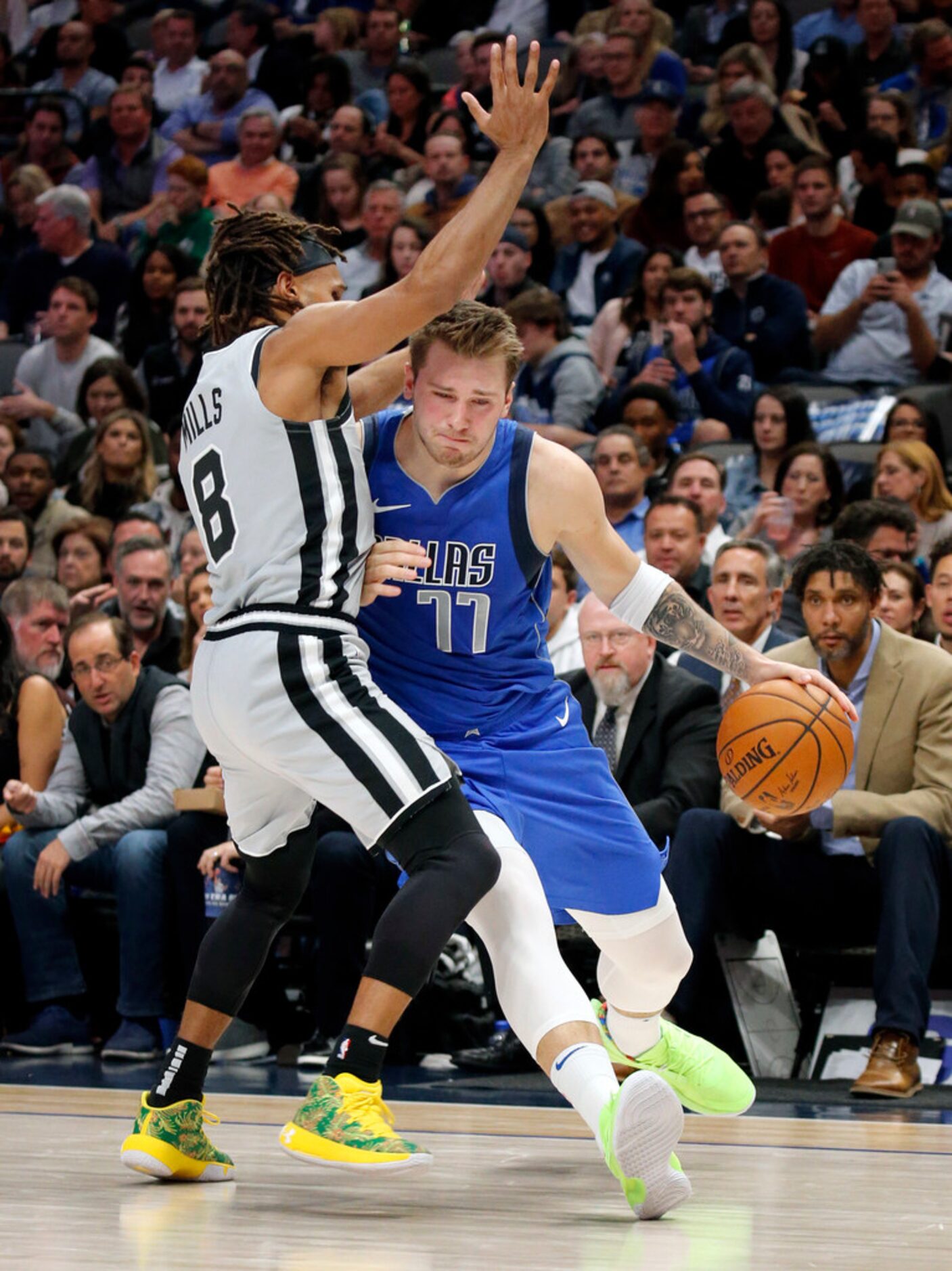 Dallas Mavericks forward Luka Doncic (77) leans into San Antonio Spurs guard Patty Mills (8)...