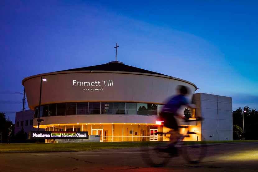 A cyclist crosses Preston Road at a stoplight as the name of Emmett Till is projected on the...