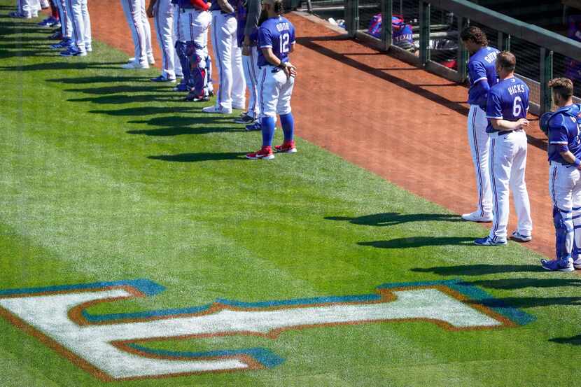 Texas Rangers players stand for the national anthem before a spring training game Cleveland...