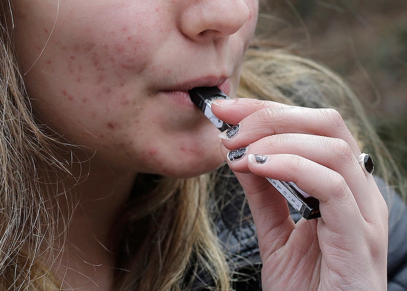 A high school student uses a vaping device near campus in Cambridge, Mass., in 2018.