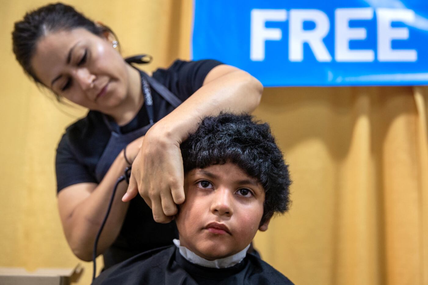 Jacob Lopez, 8 (right), receives a free haircut from Sharon Garcia during the 23rd annual...