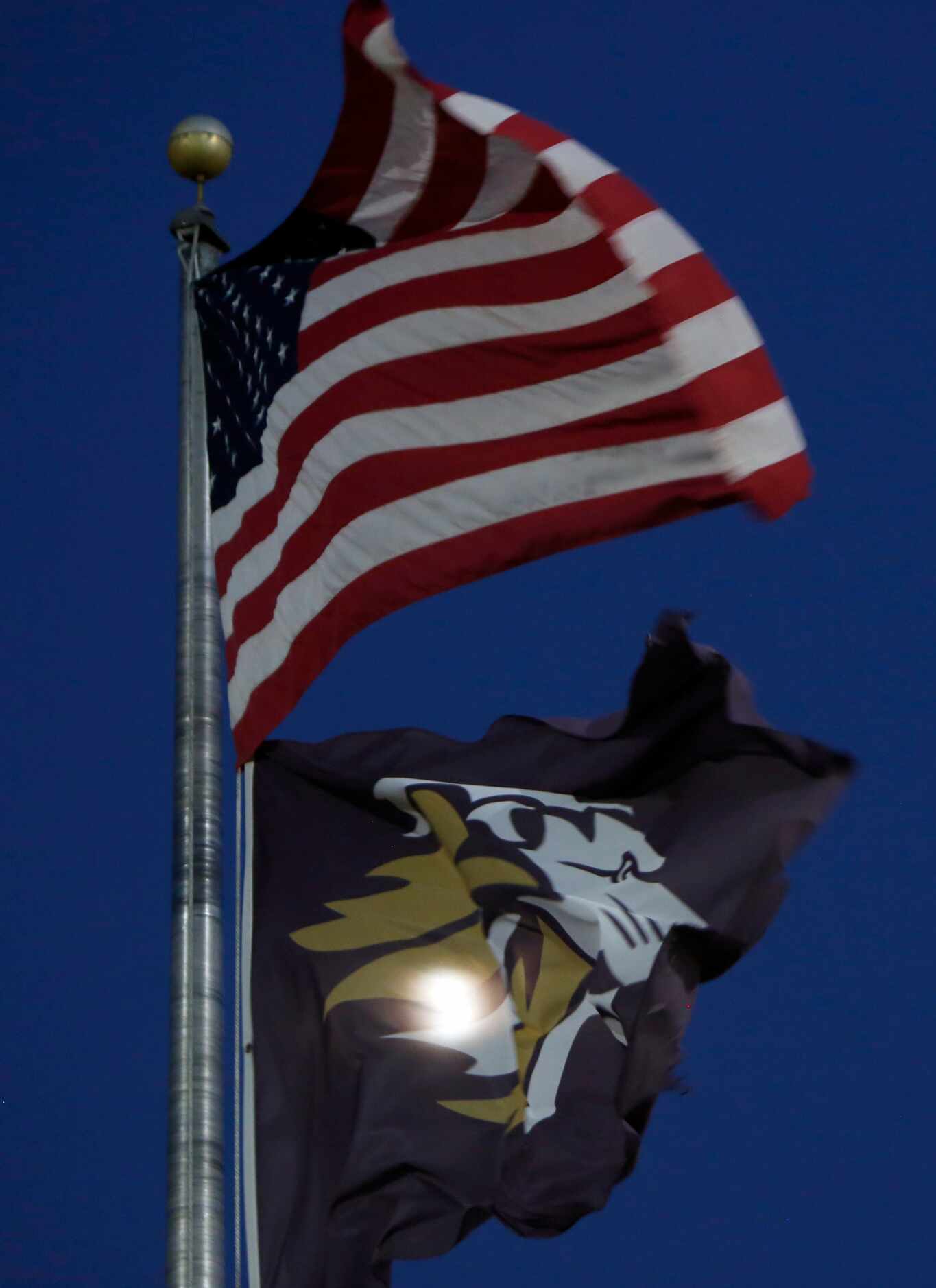 Gusty winds give the American Flag and the Kaufman Lions school flag a reason to dance as...