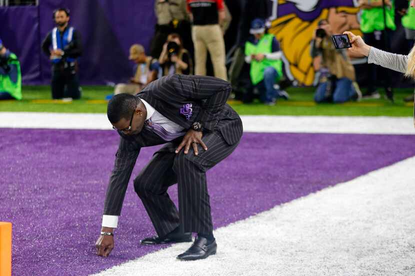 Former Dallas Cowboys Hall of Fame wide receiver Michael Irvin pulls up some keepsake turf...
