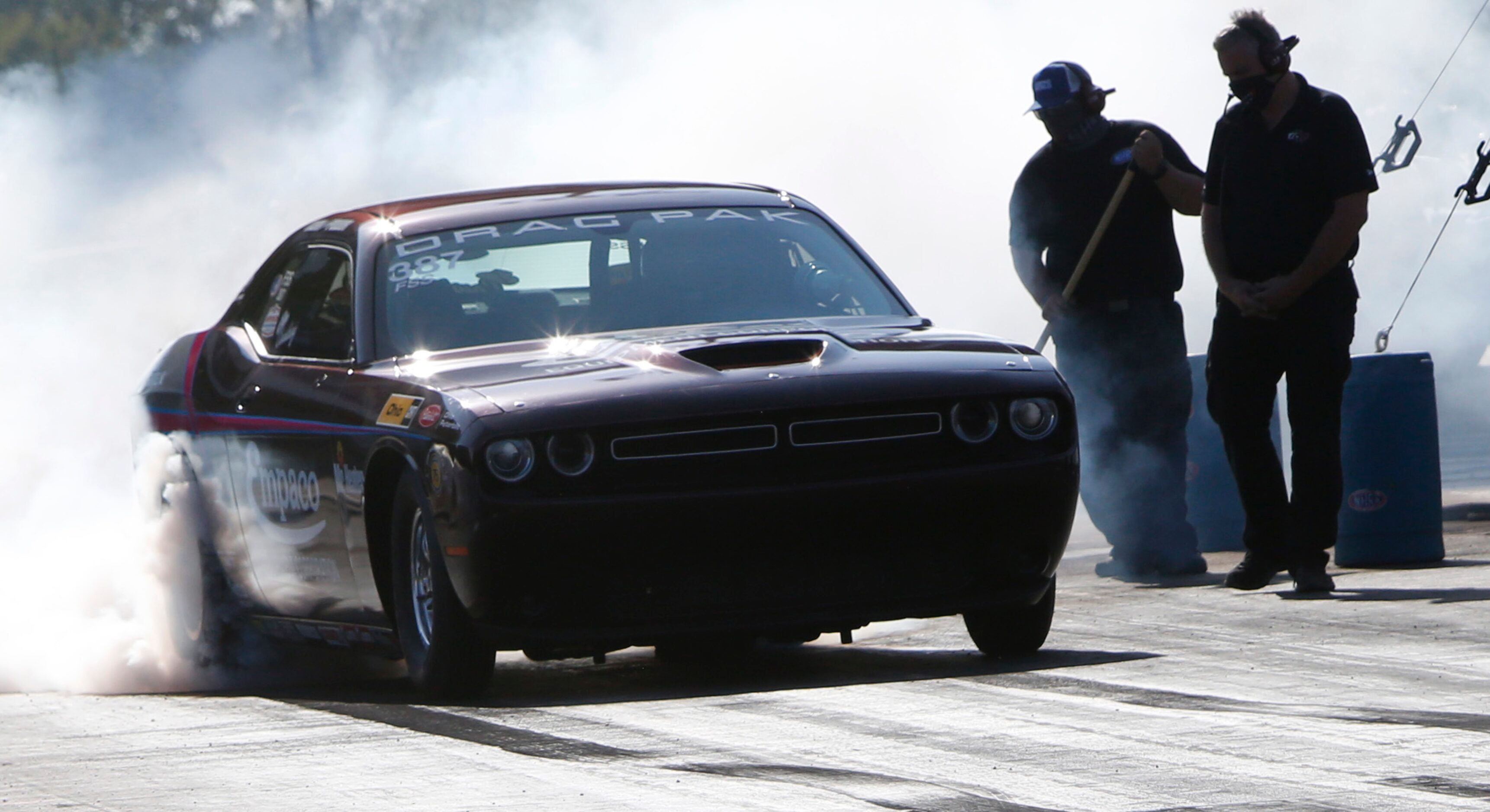 A driver heats the tires on his car prior to the start of his race as pit race team members...