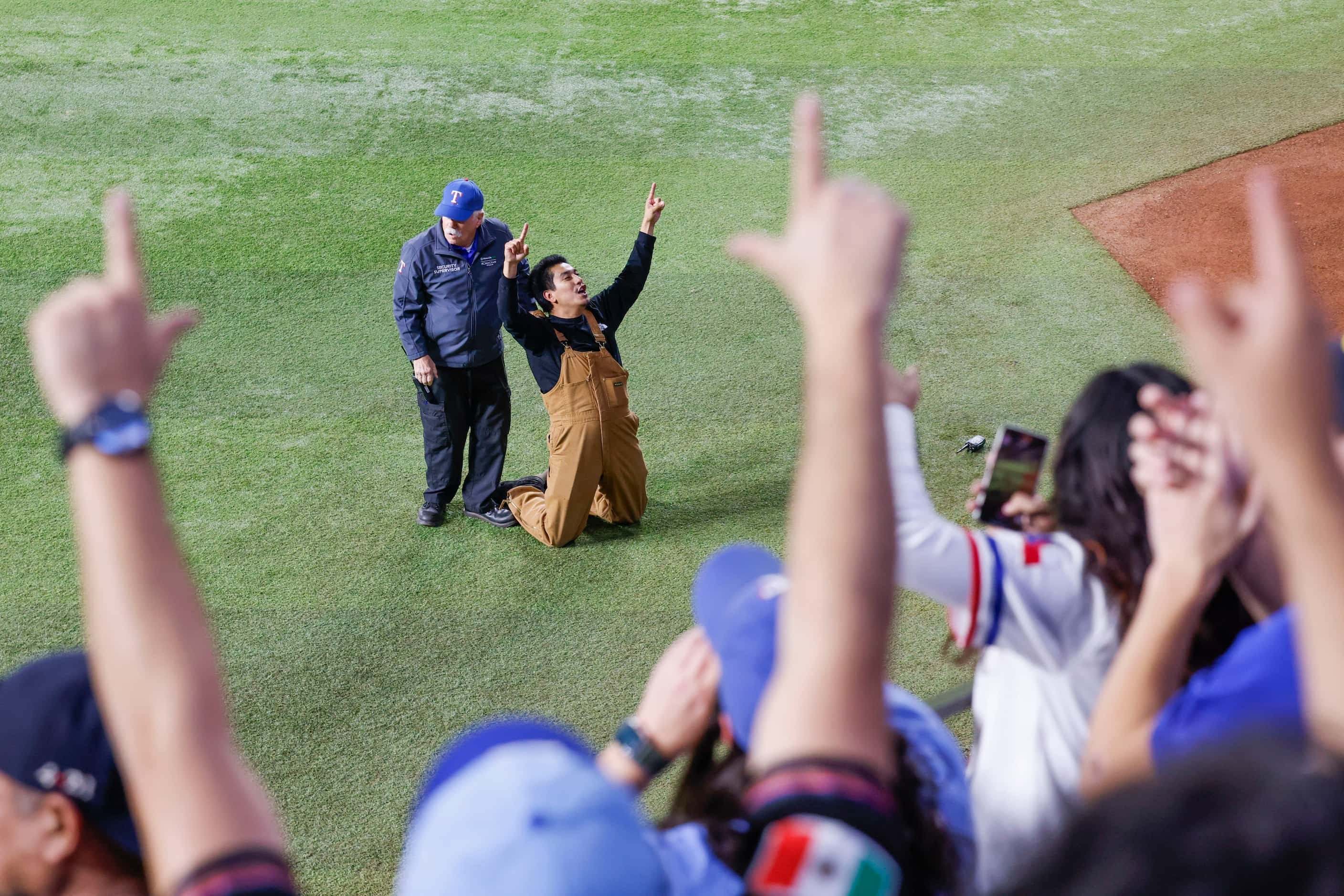 Security detains a fan who ran onto the field following Texas Rangers’ winning the World...