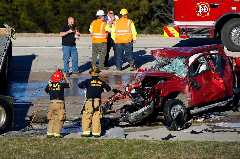 Dallas firefighters clean up after two tractor-trailers and a pickup were involved in a...