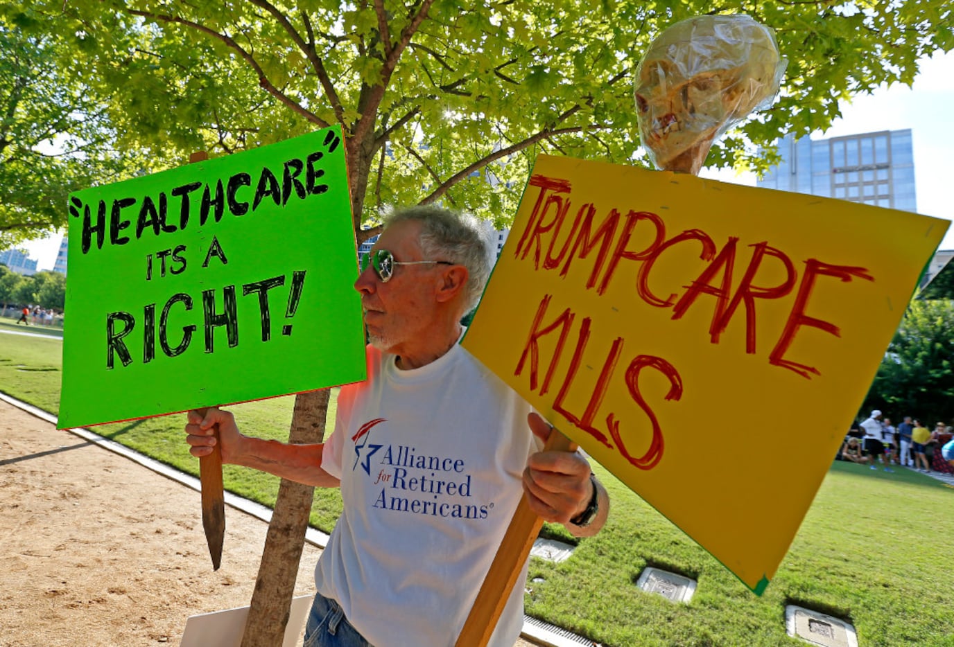 Protester Zen Biasco holds signs during a "Rally for Healthcare" event organized by the...