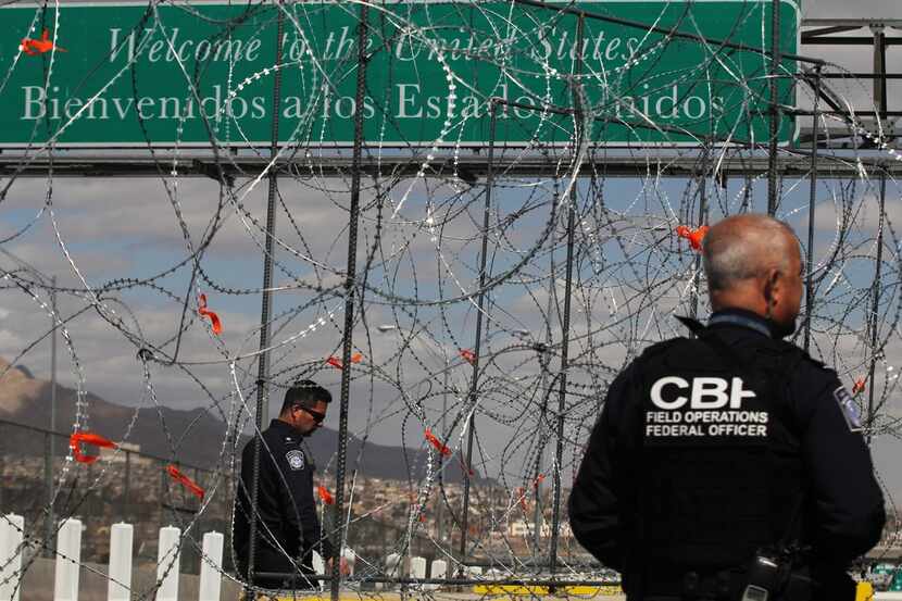 Members of the border patrol look by barbed-wire barriers that are being installed at the...