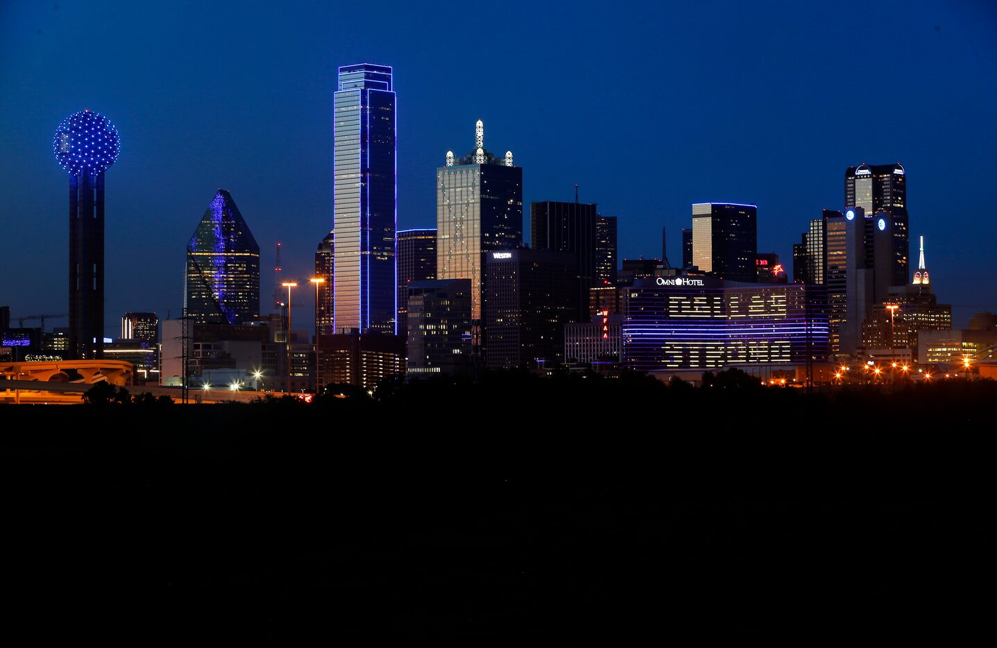 The Omni Dallas Hotel (right) reads "Dallas Strong" as the skyline of Dallas is aglow in...