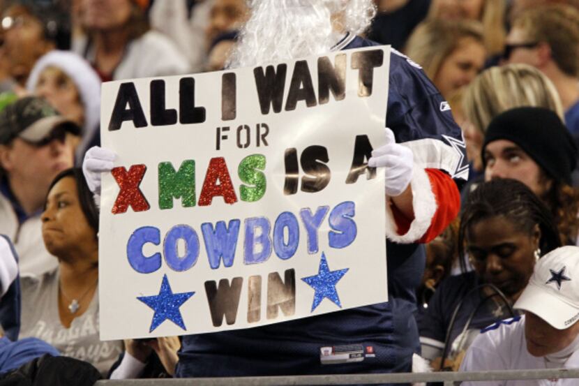 A fan in a Santa suit holds a sign that reads "all i want for xmas is a cowboys win" during...