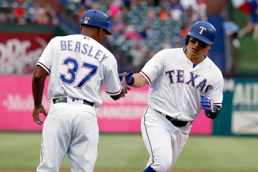 Texas Rangers third base coach Tony Beasley congratulates Shin-Soo Choo, right, who heads...