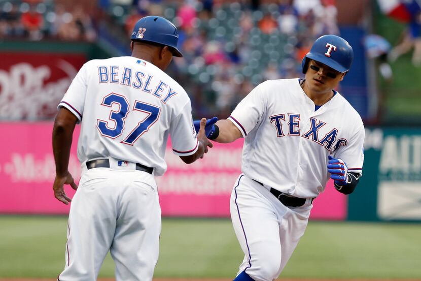 Texas Rangers third base coach Tony Beasley congratulates Shin-Soo Choo, right, who heads...