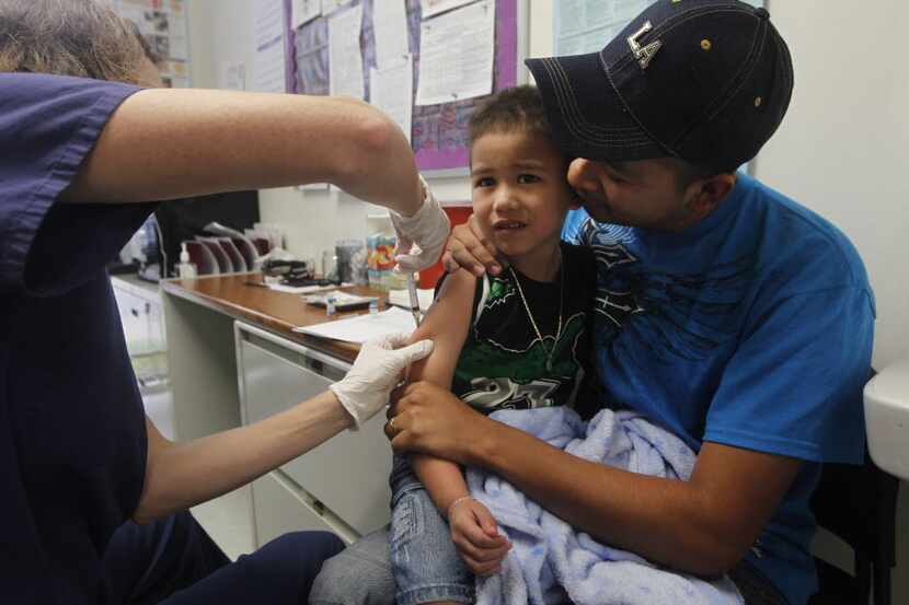 Registered nurse Nicole Kay gives Dilan Lara, 4, one of five immunizations as he is...