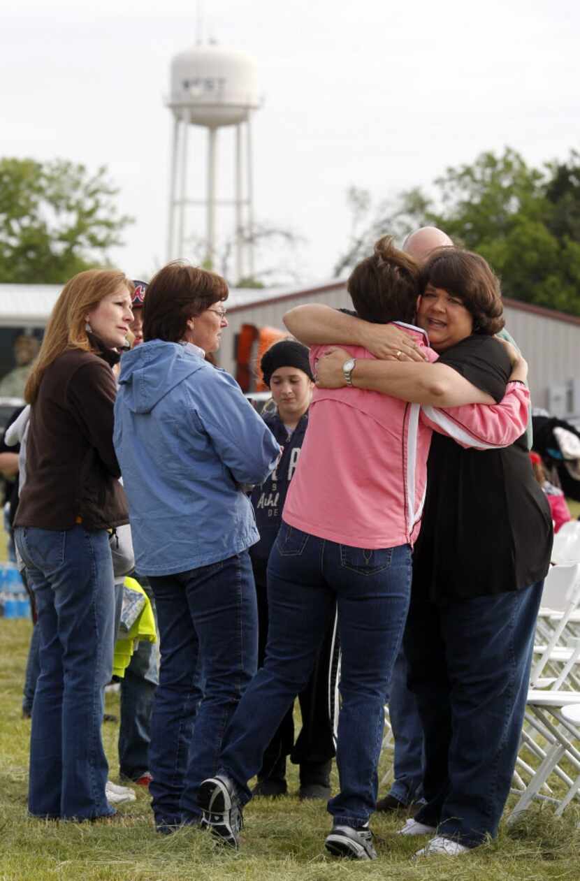 Sharon Middlebrook, center, gives a hug to the pastor's wife, Lisa Crowder, right,  prior to...