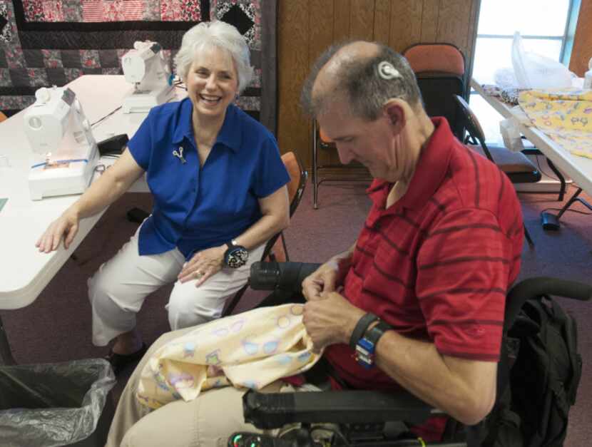 Carol Edwards helps Carlton Marshall with a dress he is making for his granddaughter during...
