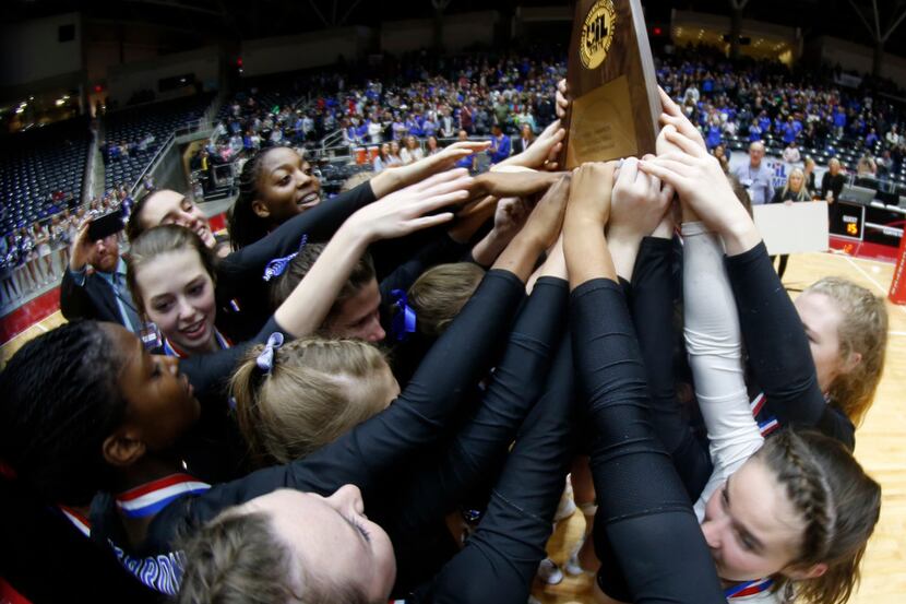 Members of the Hebron Hawks varsity volleyball team lean in to touch the Class 6A state...