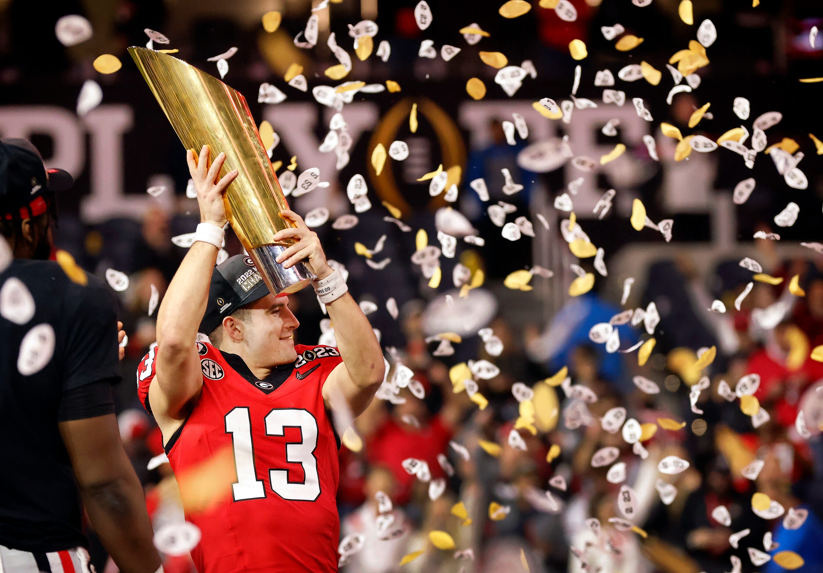 Under a hail of confetti, Georgia Bulldogs quarterback Stetson Bennett (13) raises the CFP...