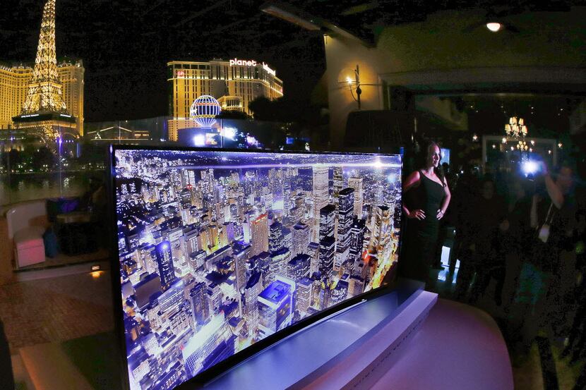 In this photo shot Sunday, Jan. 5, 2014, a model stands next to a Samsung 105-inch UHD...