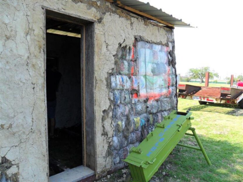 The Ubuntu-Blox machine, which operates by human power, sits beside a home made from the...