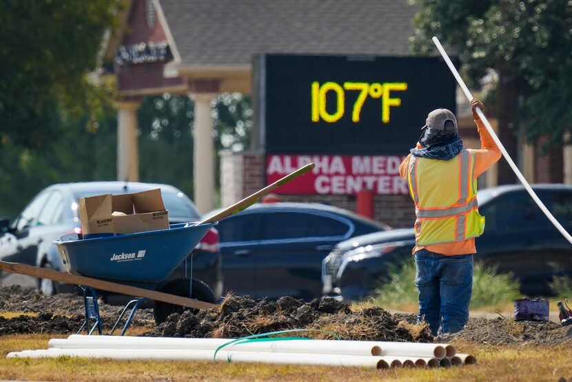 The sign on a business reads 107° as Diego Cardenas works on a construction project in the...